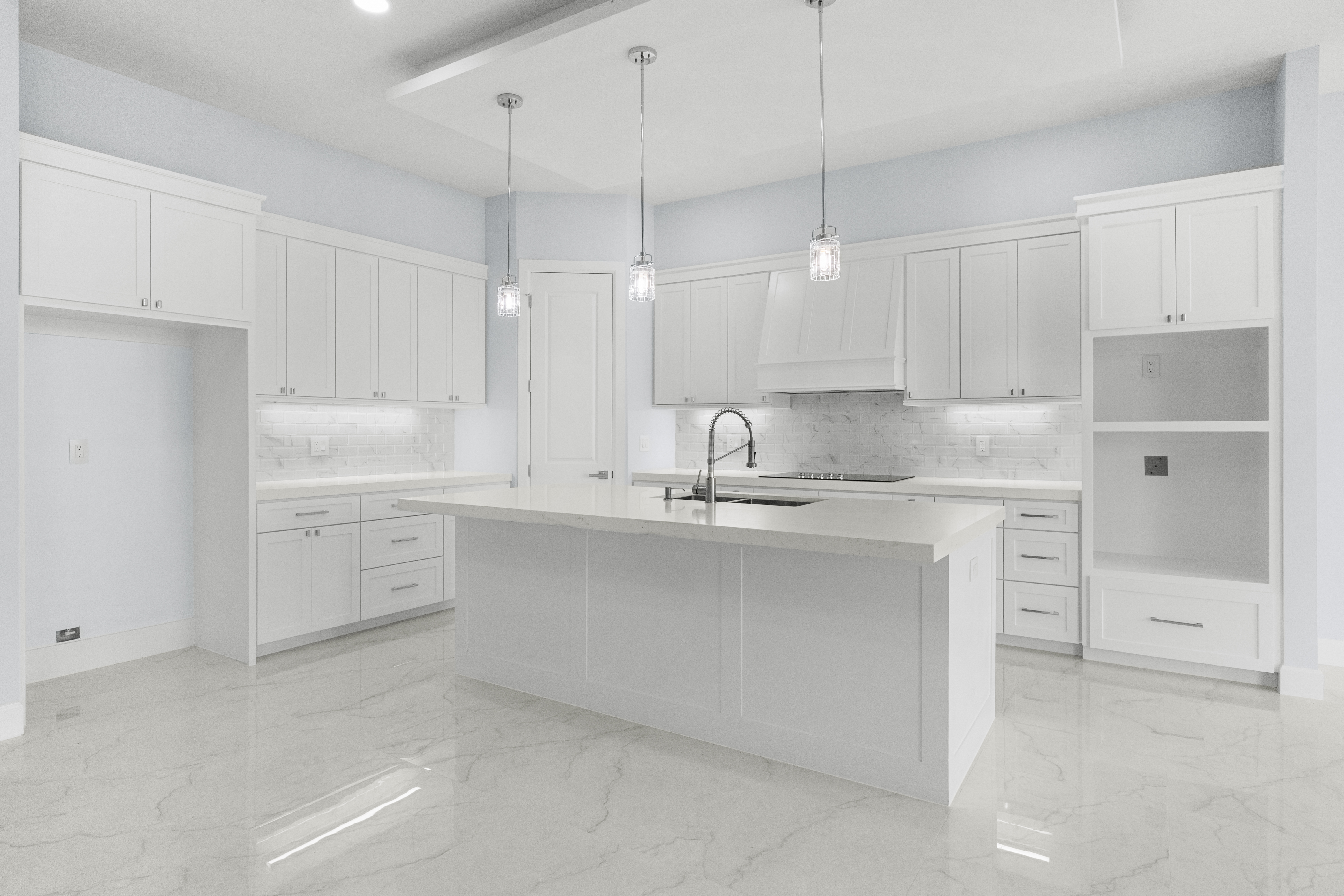 Kitchen with island, pendant lights, and custom range hood