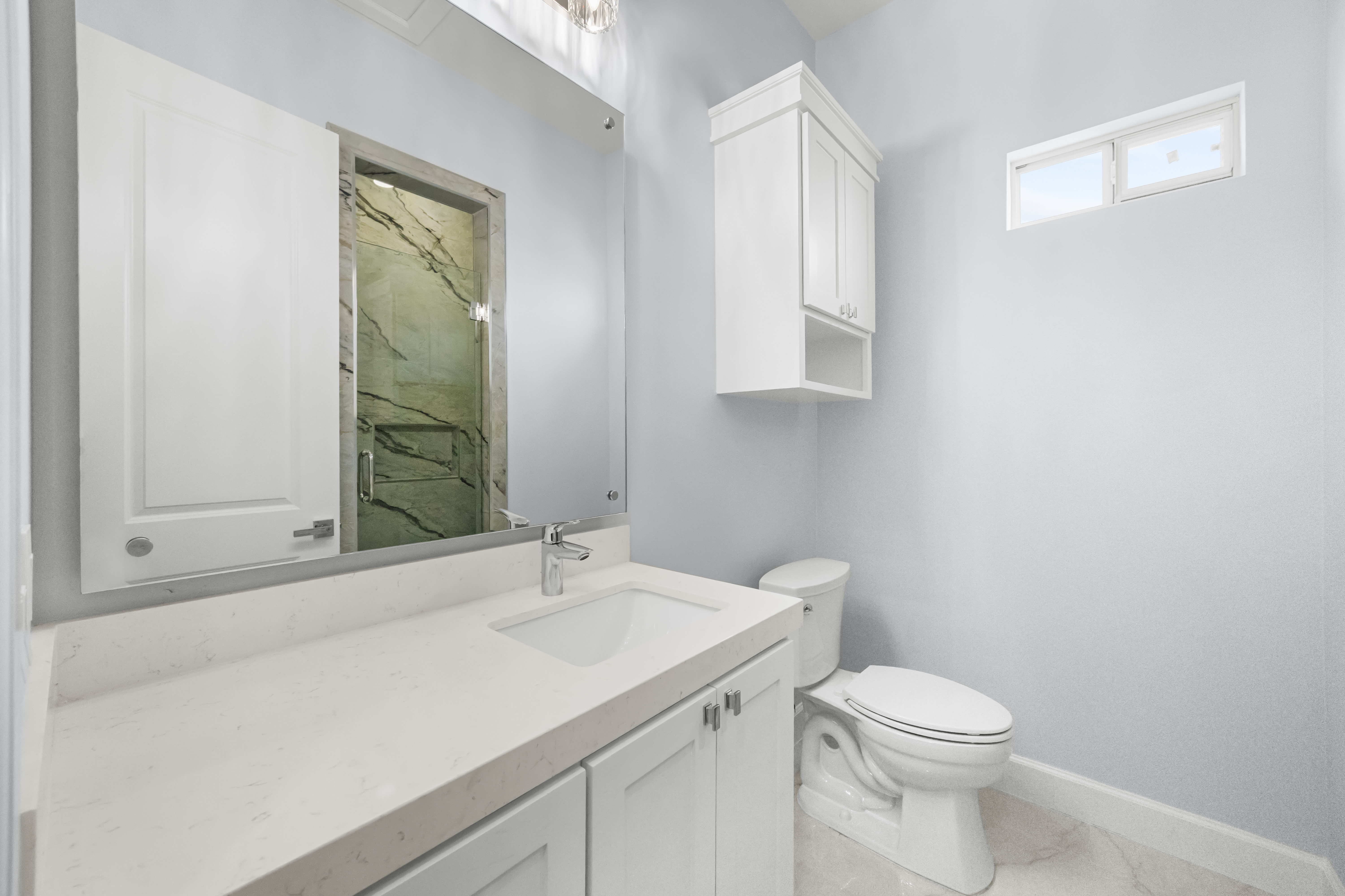 Bath vanity reflecting the green marble shower